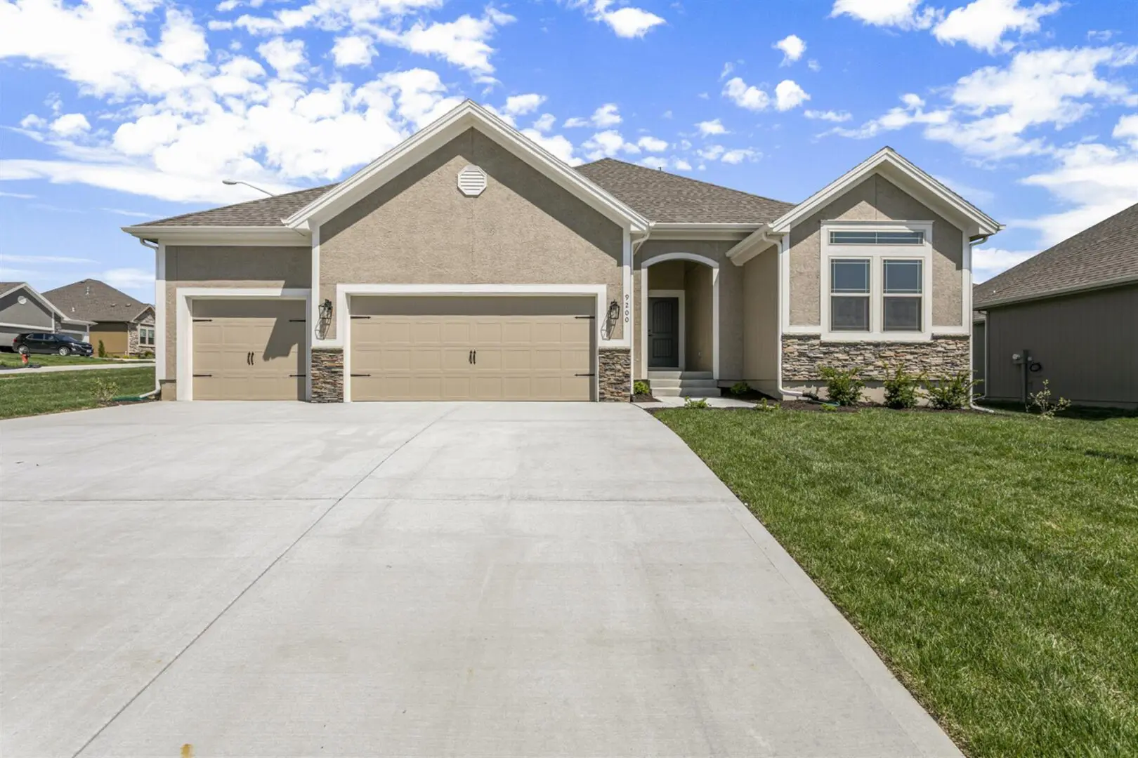 A large house with a driveway and grass in front of it.