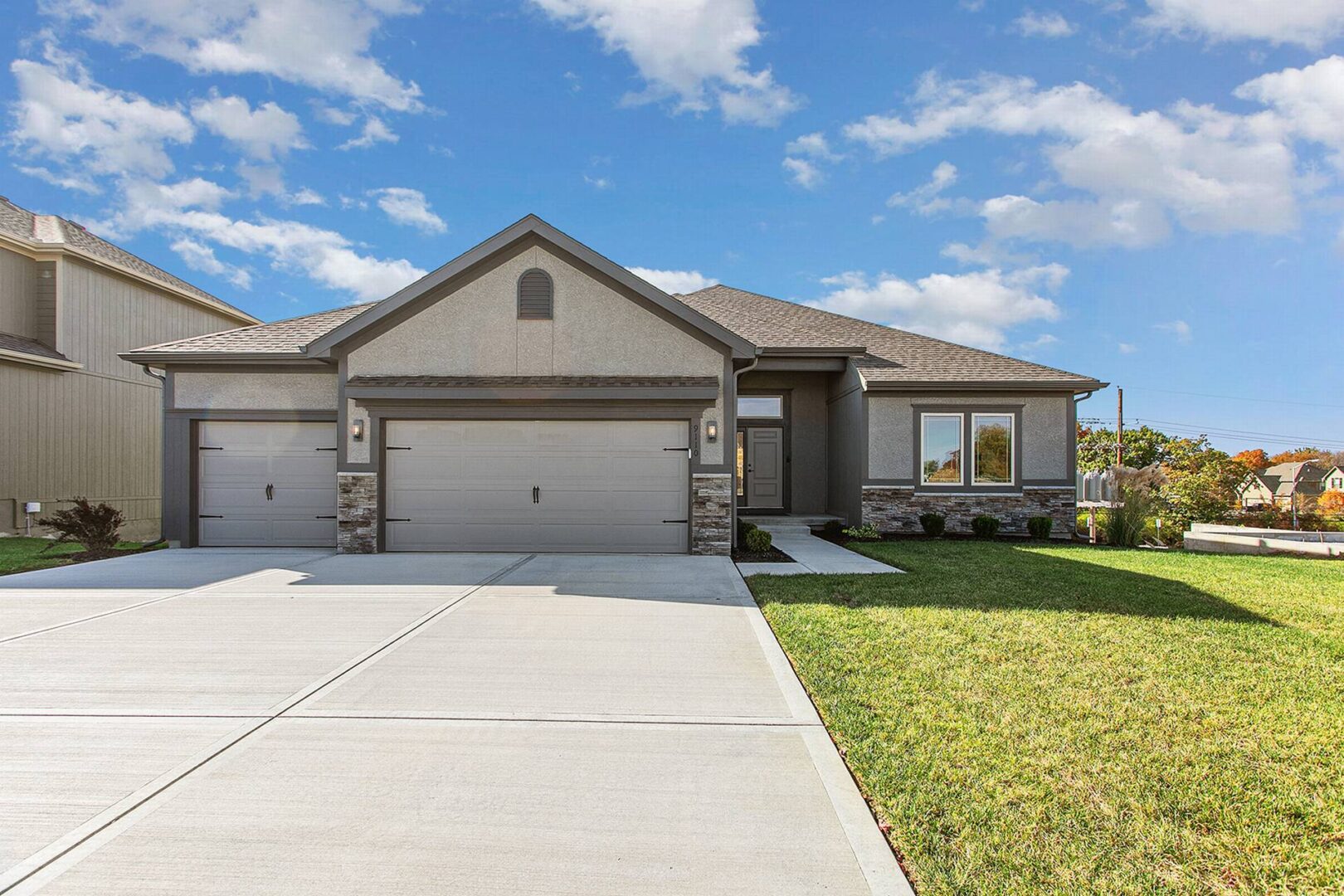 A large house with two garage doors and grass in front of it.