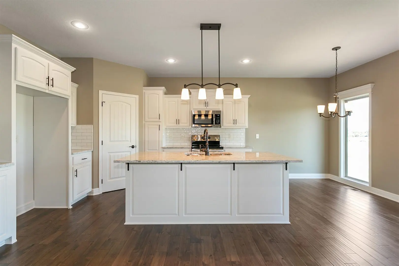 A kitchen with white cabinets and wood floors.