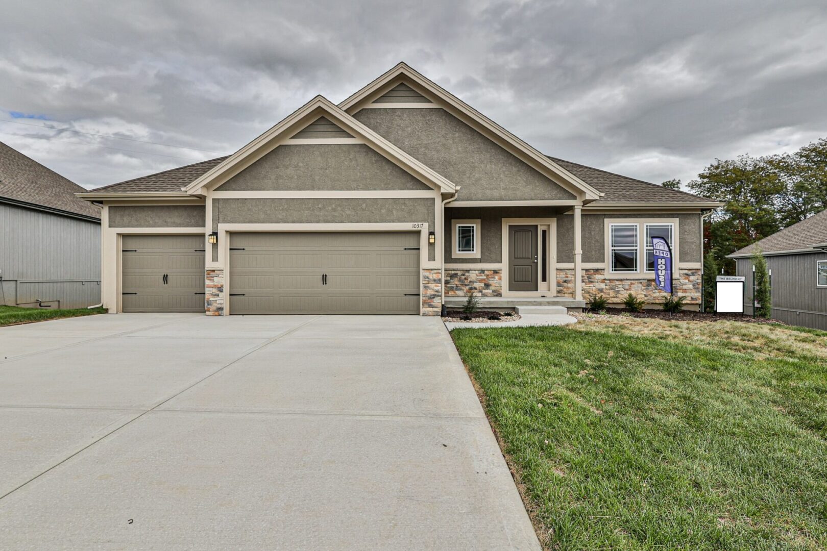 A large house with two garage doors and grass in front of it.