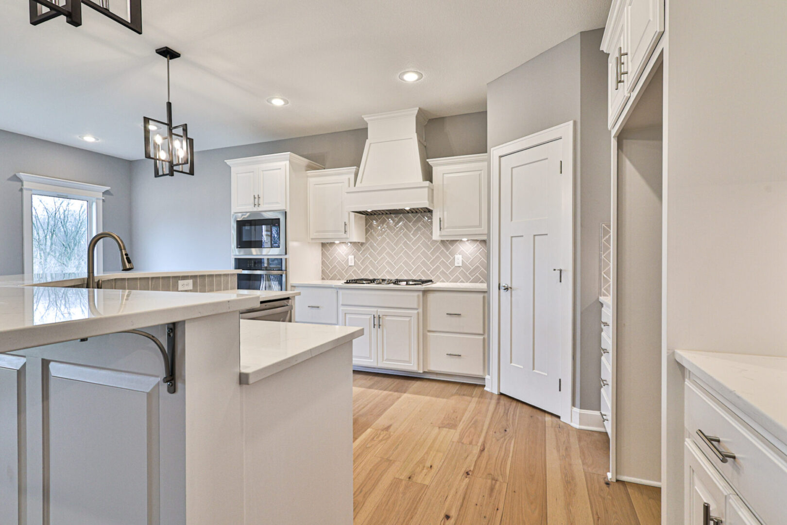 A kitchen with white cabinets and wood floors.