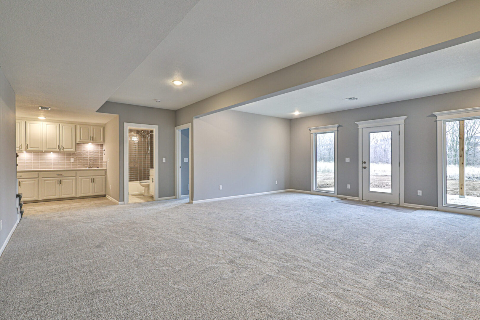 A large empty room with white walls and grey carpet.